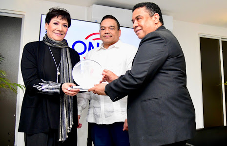 José Ruben Gonel Cosme y Armando Olivero entregan la placa de reconocimiento an Sophy.